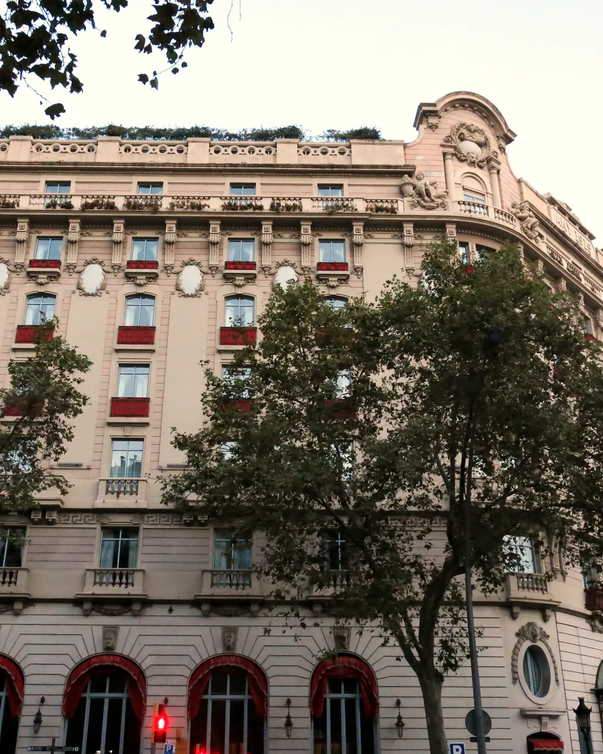 The Gran Via facade of El Palace Barcelona, with red window frames, a corner turret and red entrance awnings