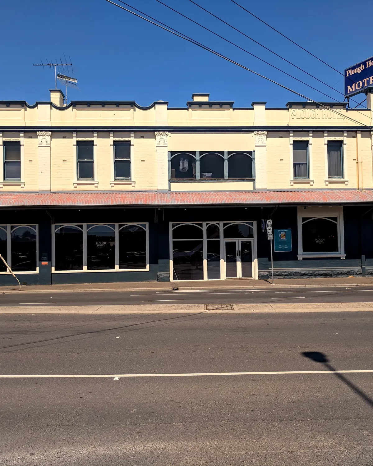 Corner pub facade of the Plough Hotel in Footscray: cream upper storey, dark ground floor and a rooftop motel sign
