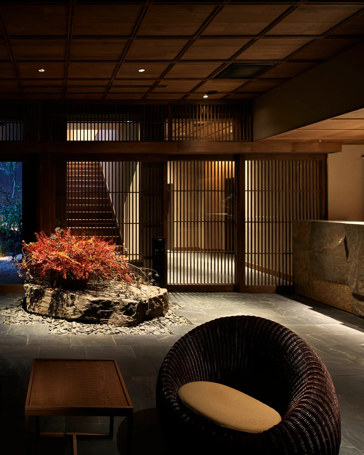 The lobby at Yuen Bettei Daita: a stone desk, a planted rock, lattice screens and a garden at night